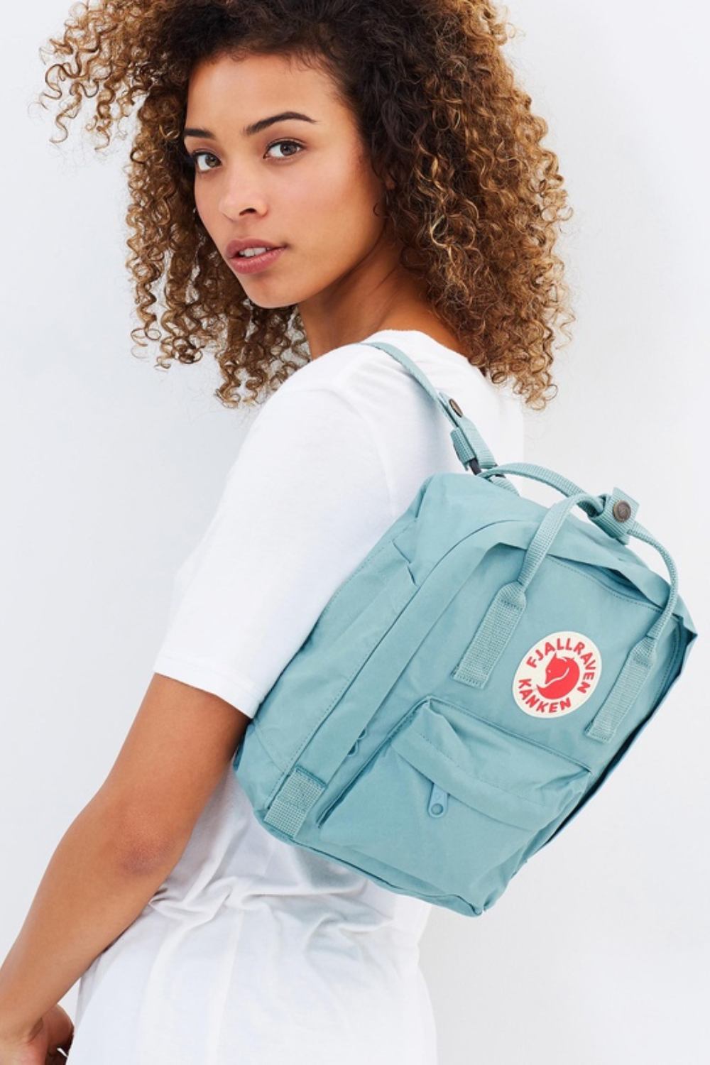 A model wearing the Fjallraven Kanken mini backpack in blue.