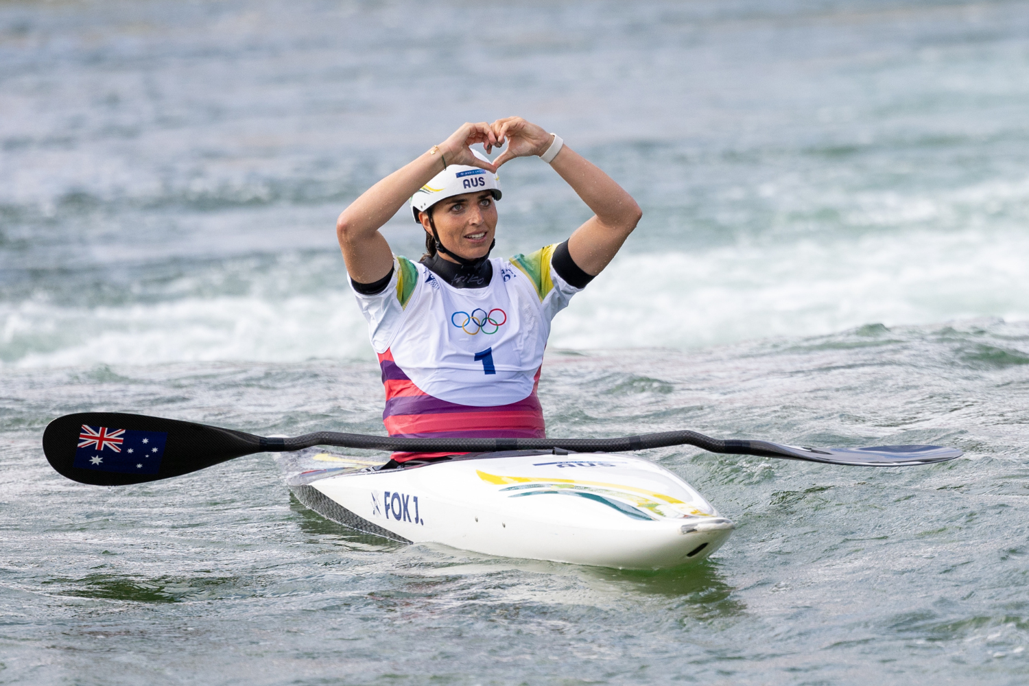 Jessica Fox making a heart symbol with her hands while in her canoe. 